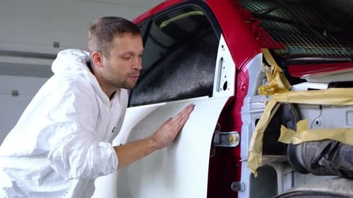 Man Smoothing Auto Body Panel on Damaged Car