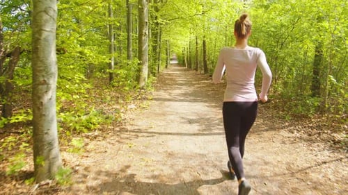 Woman Running on Forest Path