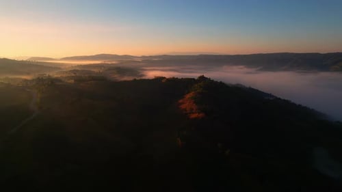 4K Aerial view from drone over mountains and sea of fog. Golden scenery at sunrise