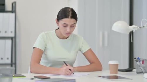 Young Woman Focused on Writing at Desk