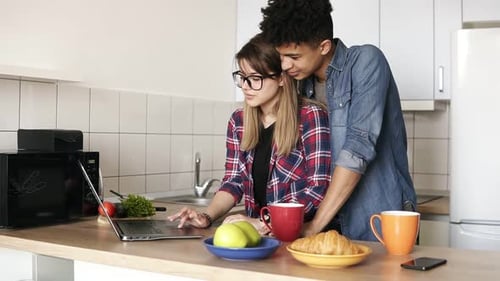 Couple Using Laptop Together in Kitchen at Home