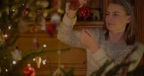 Woman Decorates Christmas Tree With Festive Ornaments