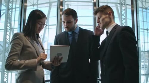 Professionals in Elevator Look at Tablet, Smartphone