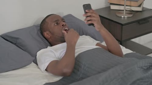 Man in Bed Shocked by Smartphone News