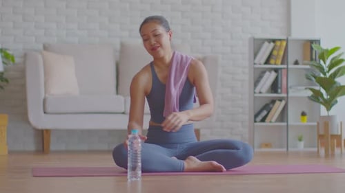 Woman Wipes Face and Drinks Water After Exercise