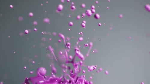 Gouttelettes de peinture violet vif éclaboussant dans l'air