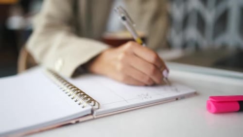 Closeup of Businesswoman Makes a Note at Notebook