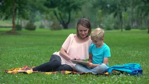 Mother and Son Using Tablet Computer in Park, Wireless Internet Access Anyplace
