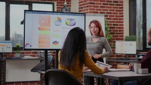 Colleagues Present Charts in Modern Office