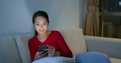 Woman Using Mobile Phone on Couch at Night