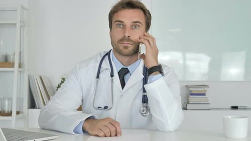 Male Doctor Talking on the Phone in Office