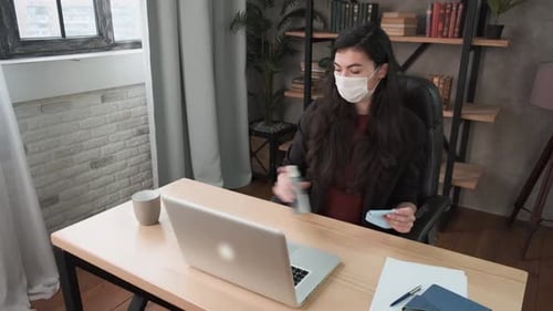 Young Adult Sanitizing Her Computer with Mask