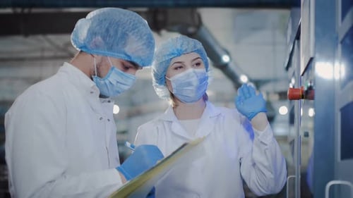 Une femme d'âge moyen enseigne à un jeune étudiant les compétences nécessaires pour travailler sur des équipements de production