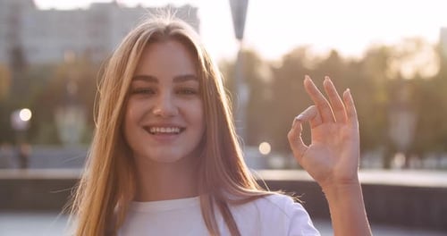 Happy Woman Makes OK Hand Gesture in City