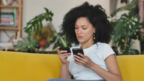 Portrait of a Young African American Woman Making an Online Purchase Using Credit Card and Phone