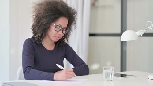 Woman Writing at Desk in Office Setting