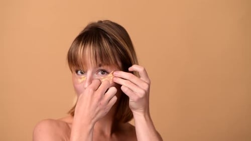 Woman Applies Gold Skincare Eye Mask Patches