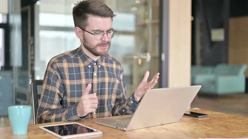 Frustrated Young Man Works at Laptop in Office