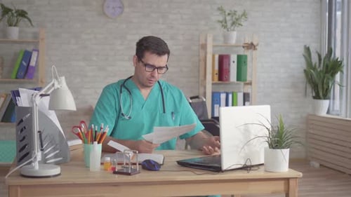 Tired Doctor Working at Desk in Office