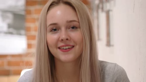 Young Blonde Woman Smiling and Waving at Camera
