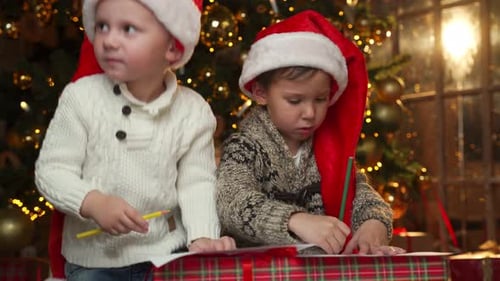 Boys in Santa Hats Writing Christmas Letters