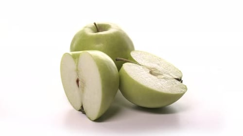 Two Fresh Cutted Green Apples are Spinning on White Background