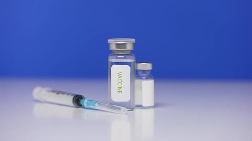 Vaccine vials and syringe on blue background