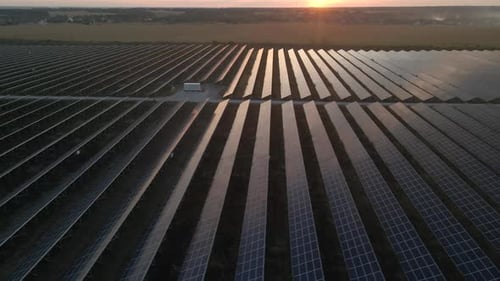 Vista aérea de un Zumbido de grandes paneles solares en una granja solar al atardecer brillante. Centrales eléctricas de células solares