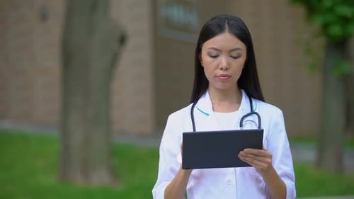 Professionelle Ärztin arbeitet am Tablet-PC im Krankenhauspark, Gesundheitswesen