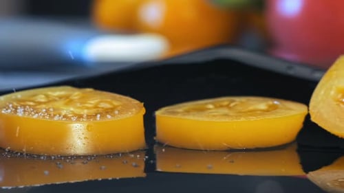 Salt Being Poured over Yellow Tomato Slices