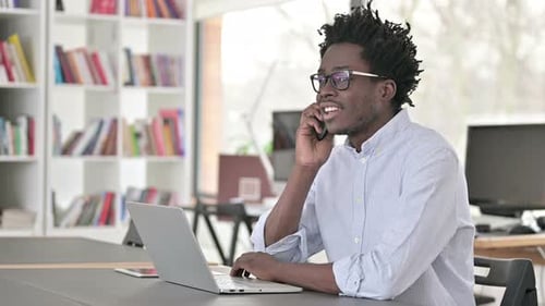Man Talking on Phone While Working on Laptop