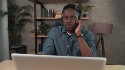 African American Man, Call Center Agent in Headset Consult Business Client Online Using Laptop