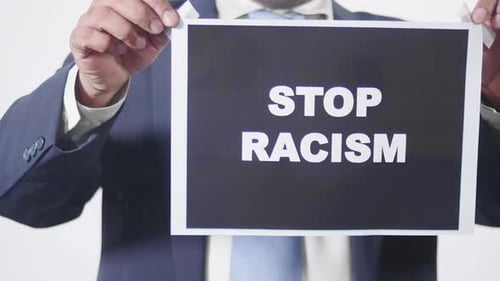Geschäftsmann stellt Schild an Glasfenster auf, um Rassismus zu verhindern