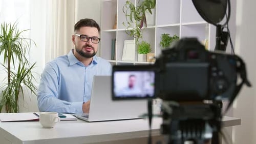 Adult Man Recording Video at Desk with Laptop