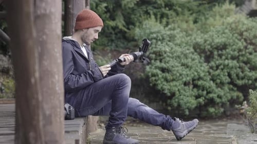 Man Assembling Camera Equipment in a Nature Setting