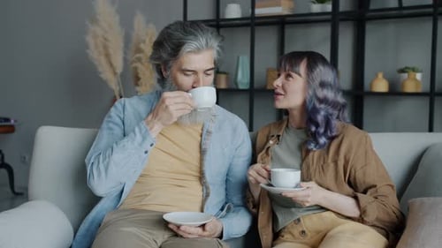 Couple Drinking Coffee and Conversing on Couch