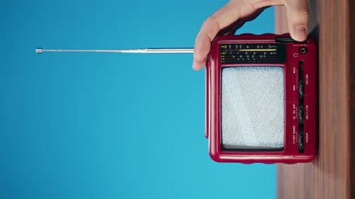Hand Turning Off Retro Red Television with Static