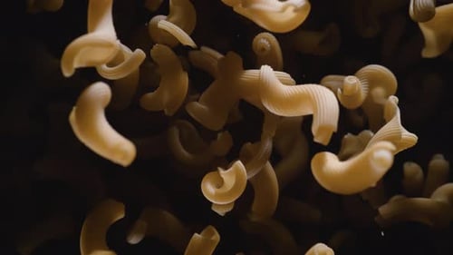 Slow Motion Dry Pasta Falling on Dark Background