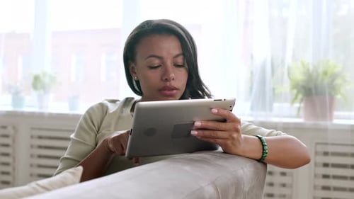 Woman Using Tablet Relaxing on Sofa at Home