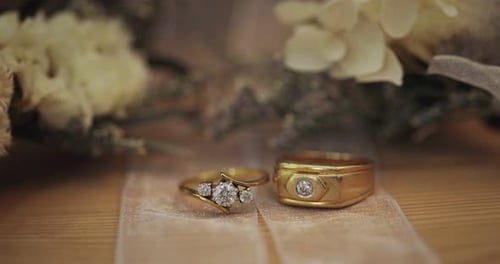 Alliances dorées avec diamants se trouvent à côté d'une fleur dans un bouquet de mariée.