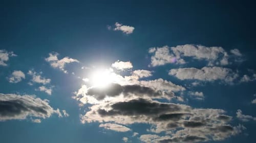 Les nuages se déplacent doucement dans le ciel bleu sur fond de soleil éclatant. Timelapse