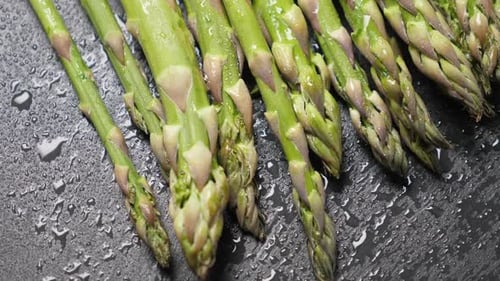 Roher grüner Spargel auf schwarzem Schieferhintergrund