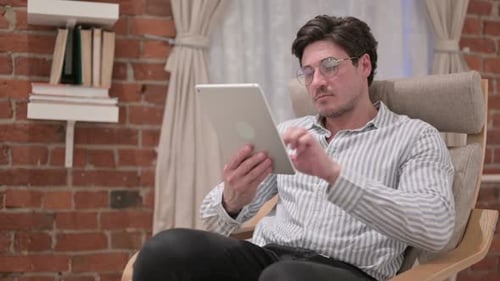 Man Using Tablet While Sitting in a Chair