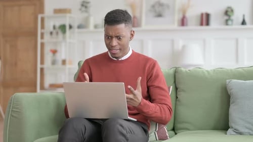 Shocked Young Adult Using Laptop on Couch