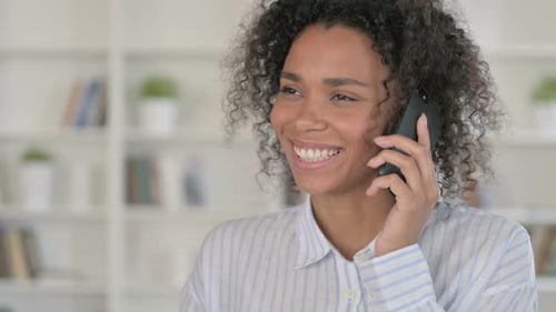Woman Smiling While Talking on Mobile Phone Indoors