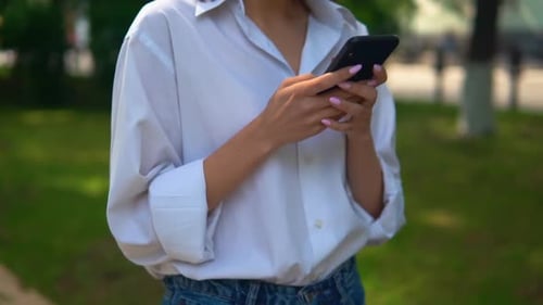 Woman Typing on Smartphone in a Park