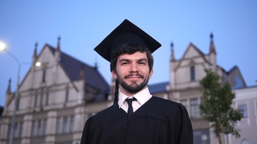 Attractive smiling male graduate standing and looking at camera