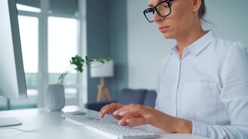 Woman Typing on a Computer at Her Desk