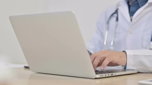 Doctor Typing on Laptop in Bright Office