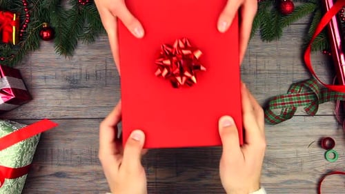 Exchanging Red Christmas Gift on Decorated Wooden Table